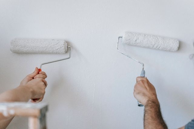 person painting a wall white 