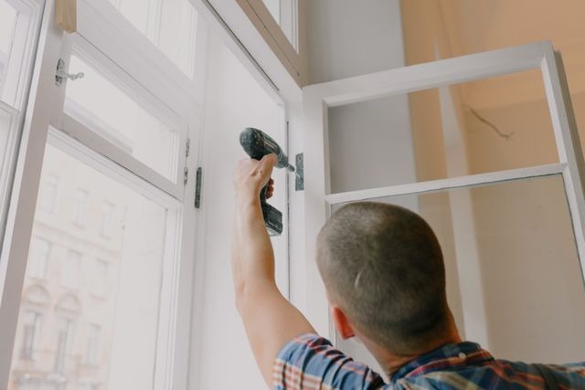 person drilling in a window hinge